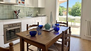 Une cuisine avec une table à manger, des chaises et une vue sur l’extérieur.