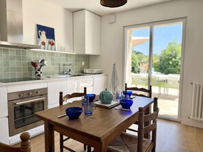 A kitchen with white cabinets, a stainless steel oven, and a dining table with blue bowls and a teapot.