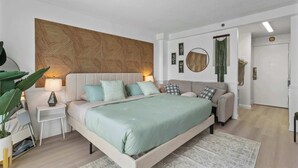 Ein modernes Schlafzimmer mit einem großen Bett, Nachttischen, einer Sitzecke und einem dekorativen Kopfteil.