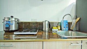 Una cocina con estufa, hervidor y una olla sobre la encimera.