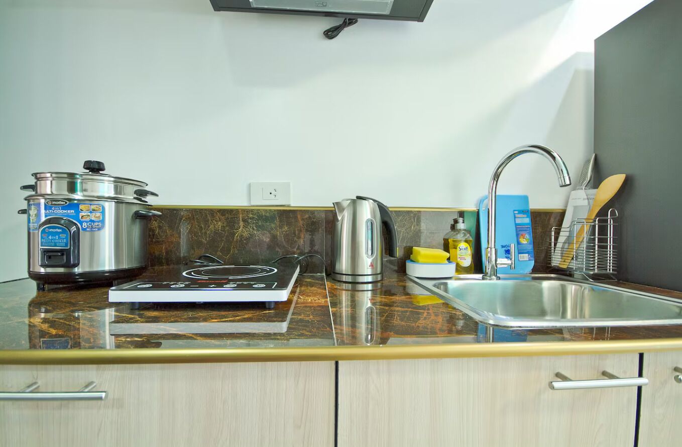A kitchen with a stove, kettle, and a pot on the counter.