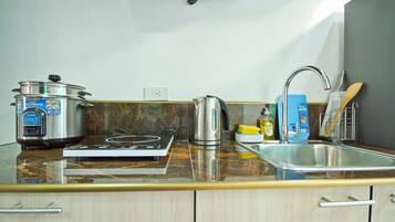 A kitchen with a stove, kettle, and a pot on the counter.