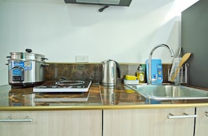 Eine Küche mit Herd, Wasserkocher und Topf auf der Arbeitsfläche.