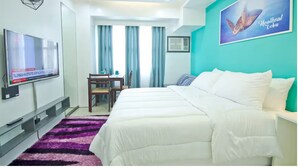 A hotel room with a bed, a TV, a desk, and a chair. - Bay Bridge View Studio 3 (Cebu City)