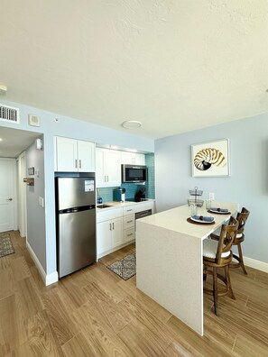 A modern kitchen with white cabinets, stainless steel appliances, and a blue backsplash. - 🐬 Beachfront Paradise, 9th Floor Apollo Condo with Gulf Views & King Bed (Marco Island)