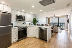 A modern kitchen with white cabinets, stainless steel appliances, and a large island. - 🦀 Highly Sought! 7th Floor Remodeled Sea Winds Beachfront, Double Vanity Sinks (Marco Island)