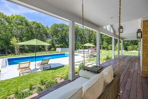 A covered outdoor area with a pool, lounge chairs, and a swing. - Brand New Osterville
Luxury Estate Sleeps 18 (Barnstable)