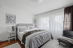 A bedroom with a bed, bedside table, lamp, and chair.