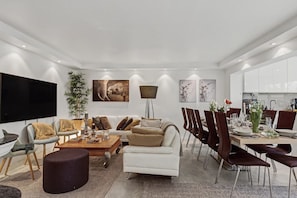 A modern living room with a sofa set, a coffee table, and a dining area with chairs and a table set for four.