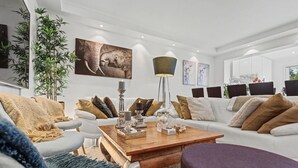 Ein modernes Wohnzimmer mit einem weißen Sofa, einem Holztisch und einem großen Elefantenbild.