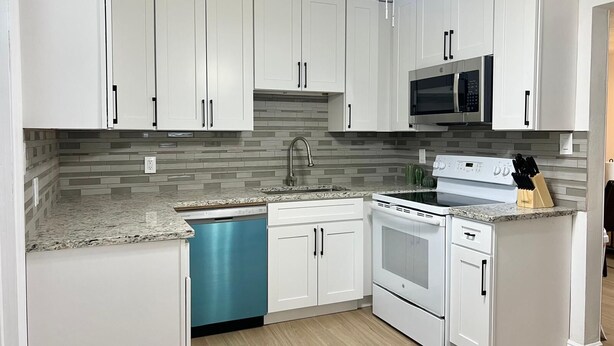 A kitchen with white cabinets, a microwave, a dishwasher, and a stove. - Peacefull & Central 2-bedroom house with AC in sunny Tampa (Tampa)