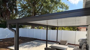 A covered patio area with outdoor furniture, including a table and two chairs, and a grill. - Peacefull & Central 2-bedroom house with AC in sunny Tampa (Tampa)