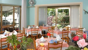 A dining area with tables set for a meal, featuring a variety of fruits, vegetables, and pasta. - Hotel Latini (Rimini)