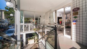 A modern hotel lobby with a glass railing, a staircase, and a view of the street. - Hotel Latini (Rimini)