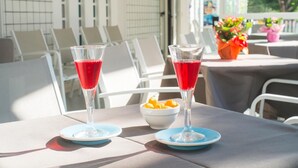 Two glasses of red beverage on a table with a bowl of fruit. - Hotel Latini (Rimini)