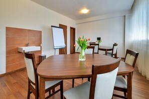 A conference room with a wooden table, chairs, a whiteboard, and a vase with flowers. - Klar Hotel (Liptovsky Mikulas)