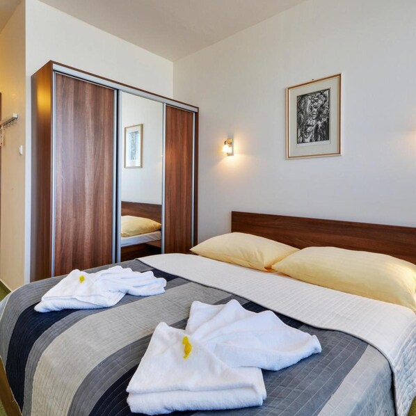 A hotel room with a bed, a wardrobe, a bedside lamp, and a framed picture on the wall. - Klar Hotel (Liptovsky Mikulas)