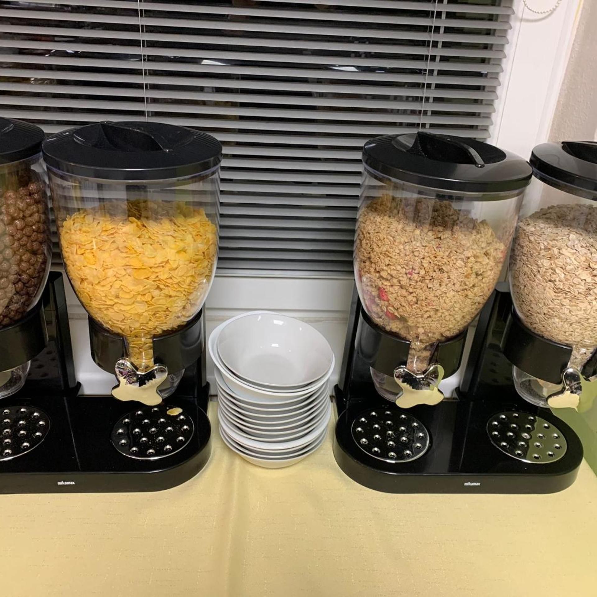 Een bedieningsstation voor eten met drie bakken, gevuld met verschillende soorten voeding, en een stapel witte borden ernaast.