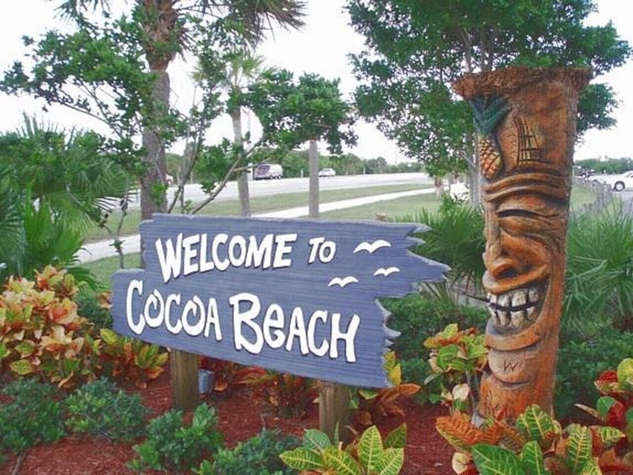 En välkomstskylt för Cocoa Beach, tillverkad av trä och försedd med ett utskuret ansikte.