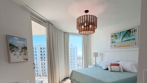 Una camera da letto con un letto grande, vista sulla città e un dipinto raffigurante una spiaggia.