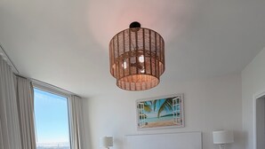A bedroom with a large window, a bed with a green bedspread, two bedside tables with lamps, and a hanging light fixture. - 💎renovated paradise! 10th floorOcean View & lagoon view @ the Palms of Destin🌅🌴 (Destin)