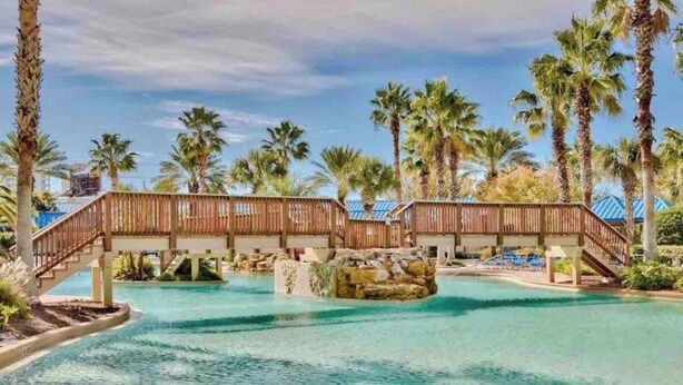 A resort pool with wooden bridges and palm trees. - 💎renovated paradise! 10th floorOcean View & lagoon view @ the Palms of Destin🌅🌴 (Destin)