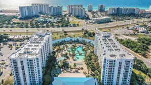 Un hotel di grandi dimensioni con una piscina centrale circondata da palme e vista sull'oceano.