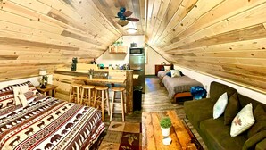 Ein gemütliches Blockhaus-Interieur mit einem Bett, einer Couch, einer Bar und einer kleinen Küche.