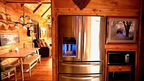 A wooden interior with a stainless steel refrigerator, a heart-shaped decoration, and a dining area with a table and chairs. - Cozy RRG Cabin Hot Tub  Dog Run No-Step Entry (Powell County)