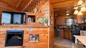 A cozy cabin interior with a wooden staircase, a fireplace, a kitchen area, and a dining space. - Cozy RRG Cabin Hot Tub  Dog Run No-Step Entry (Powell County)