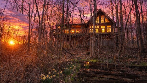 A wooden cabin surrounded by trees with a sunset in the background. - Cozy RRG Cabin Hot Tub  Dog Run No-Step Entry (Powell County)