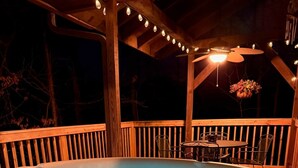 A hot tub in a covered outdoor area with wooden railings and string lights. - Cozy RRG Cabin Hot Tub  Dog Run No-Step Entry (Powell County)