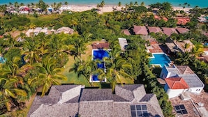 An aerial view of a resort with multiple buildings, a swimming pool, and a beach. - Exclusive house in Arraial d'Ajuda: 7 bedrooms, sea view and modern rustic design. (Arraial d'Ajuda)