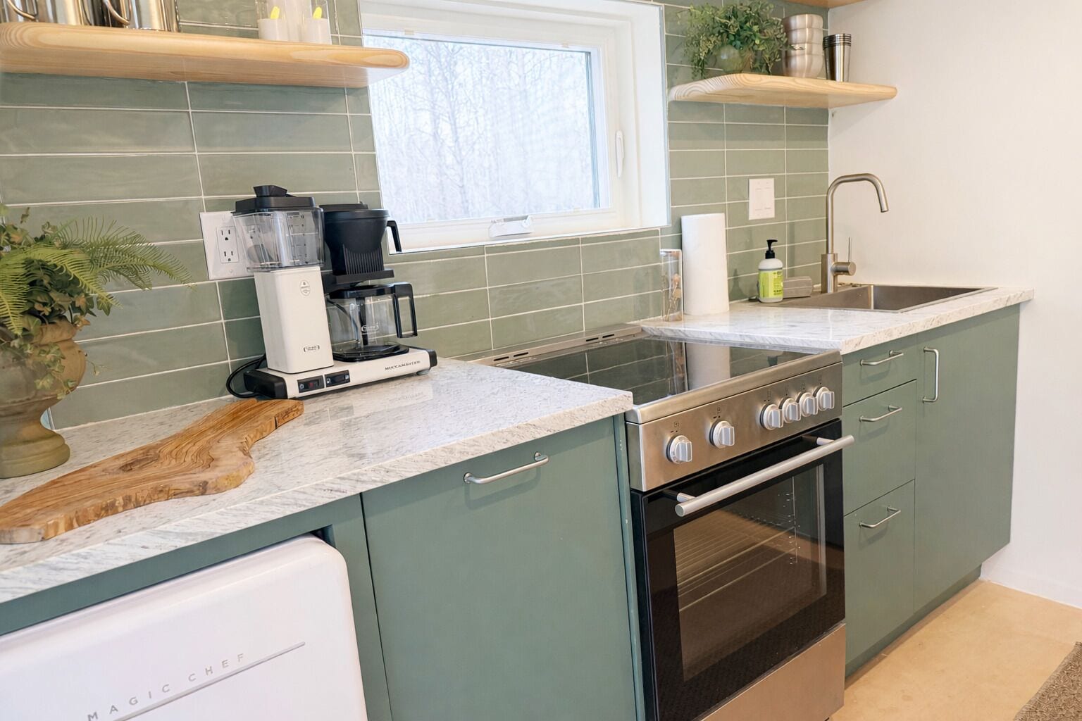 A modern kitchen with a coffee maker, a stove, and a dishwasher.