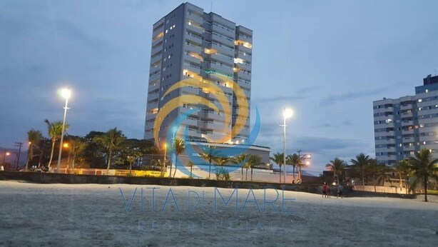 Un grand hôtel à plusieurs étages, une plage au premier plan et des palmiers.
