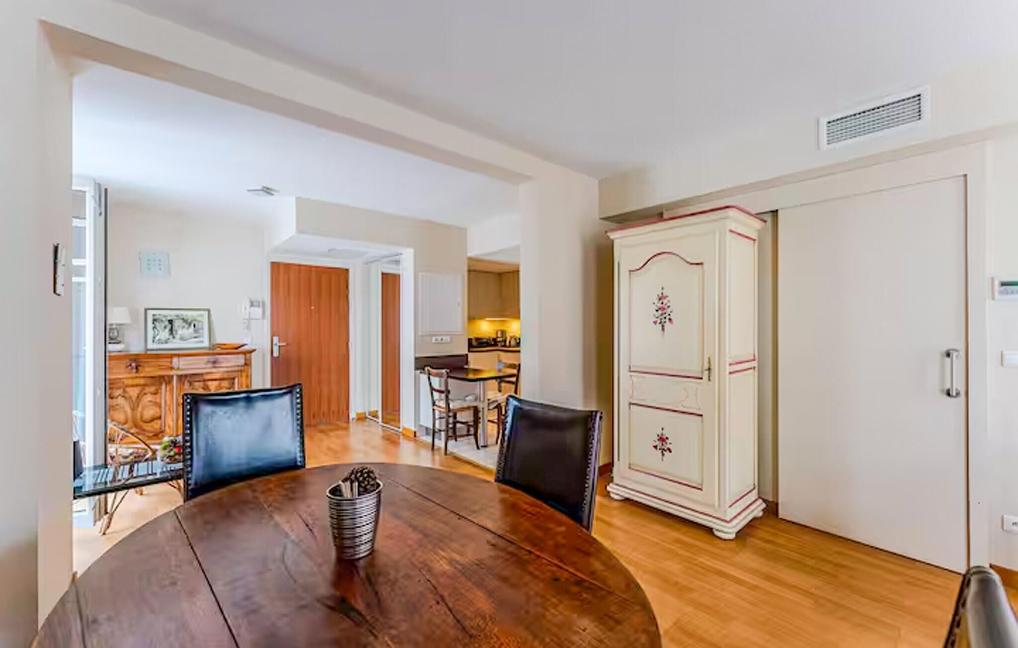 Un coin repas comprenant une table en bois, des chaises et un buffet orné de motifs floraux.