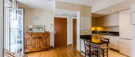 A modern kitchen with a dining area, wooden cabinet, and a view through a glass door.