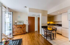 A modern kitchen with a dining area, wooden cabinet, and a view through a glass door. - 1 bedroom beautiful apartment in Arcachon (Arcachon)