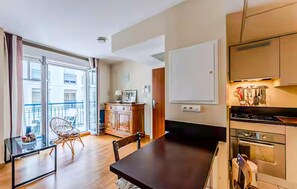 A modern apartment with a dining area, kitchen, and a balcony with a chair. - 1 bedroom beautiful apartment in Arcachon (Arcachon)