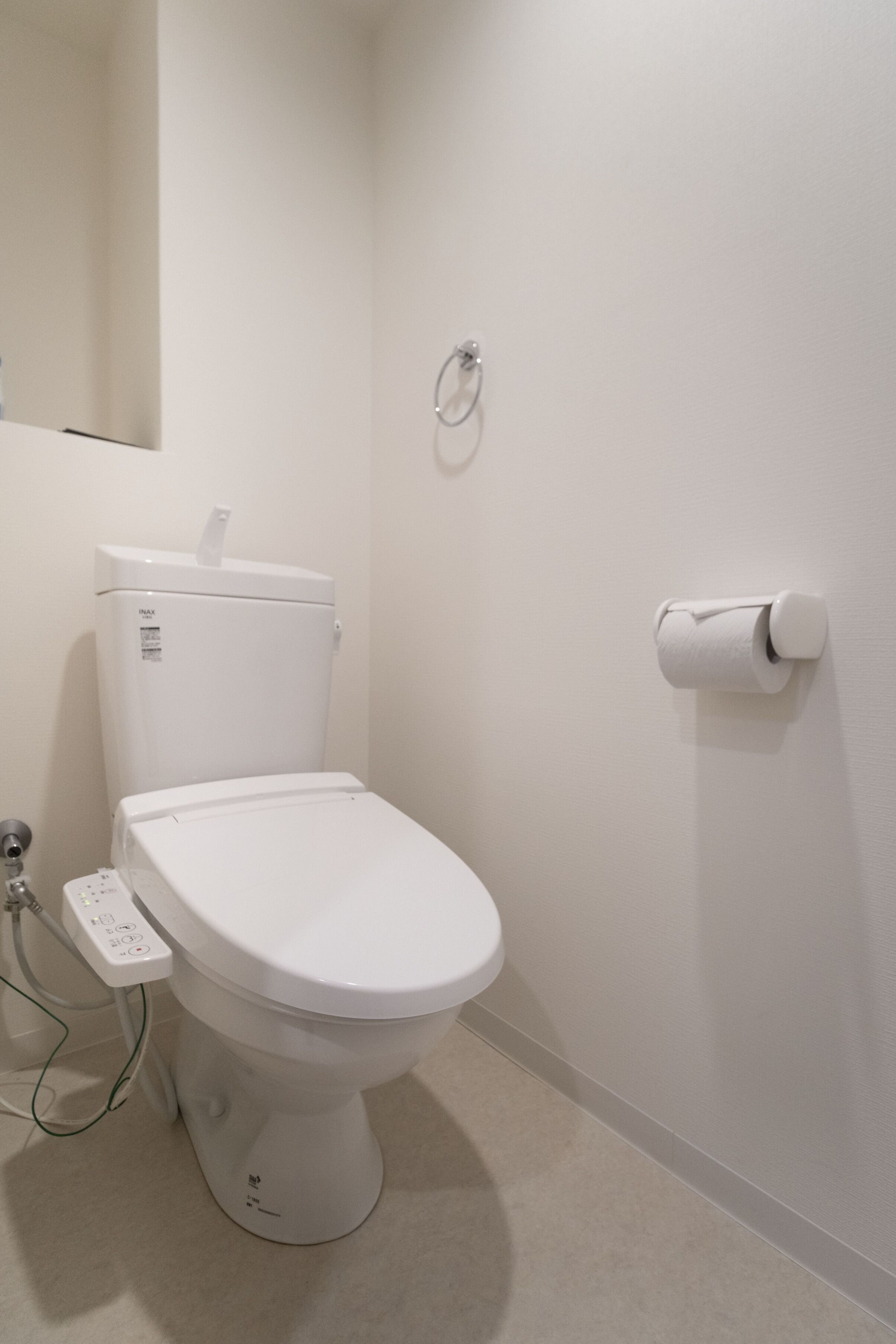 Een moderne badkamer met een wit toilet, een toiletrolhouder en een zichtbare boiler.