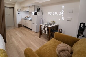 A compact living space with a kitchenette, a dining area, and a sofa with a throw blanket. - The Peak Dotonbori (Osaka)