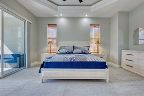 Een slaapkamer met een bed, nachtlampjes, een dressoir en een groot raam met jaloezieën.