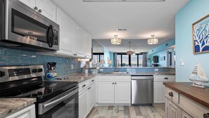 Een moderne keuken met witte kasten, roestvrijstalen apparatuur en een blauwe tegelachtergrond.