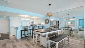 Een ruime keuken met een centraal eiland, houten stoelen en een eettafel.