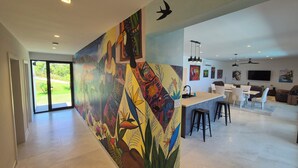 A modern kitchen with a central island, bar stools, and a dining area with chairs. - Stunning seaside villa with jacuzzi (Boca Chica)