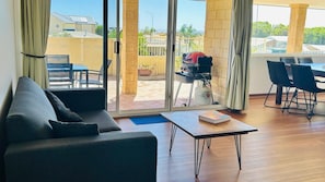 A modern living room with a sofa, a coffee table, and a dining area with chairs and a table. - Sea Views Holiday Home- South Bunbury (South Bunbury)
