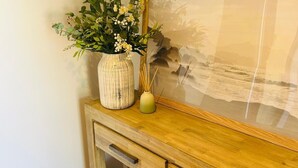 Un meuble en bois surmonté d’un vase de fleurs et d’un cadre photo.