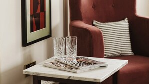 A room with a red armchair, a table with glasses, and framed artwork on the wall. - The Hillbrook Sherborne (Sherborne)