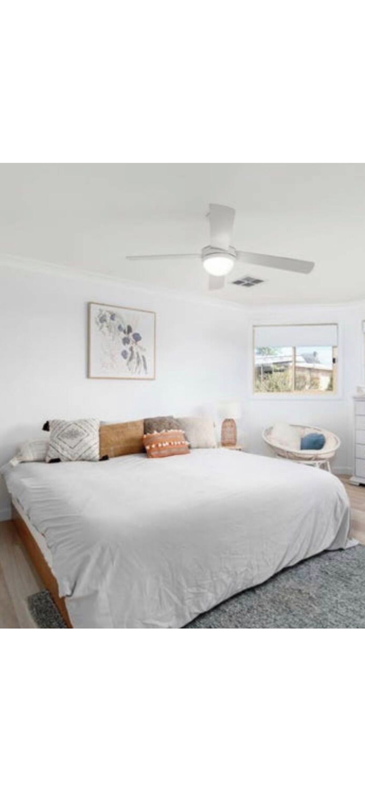 A bedroom with a bed, a ceiling fan, a window, and a wall-mounted picture.