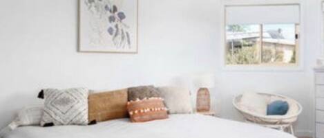 A bedroom with a bed, a ceiling fan, a window, and a wall-mounted picture.